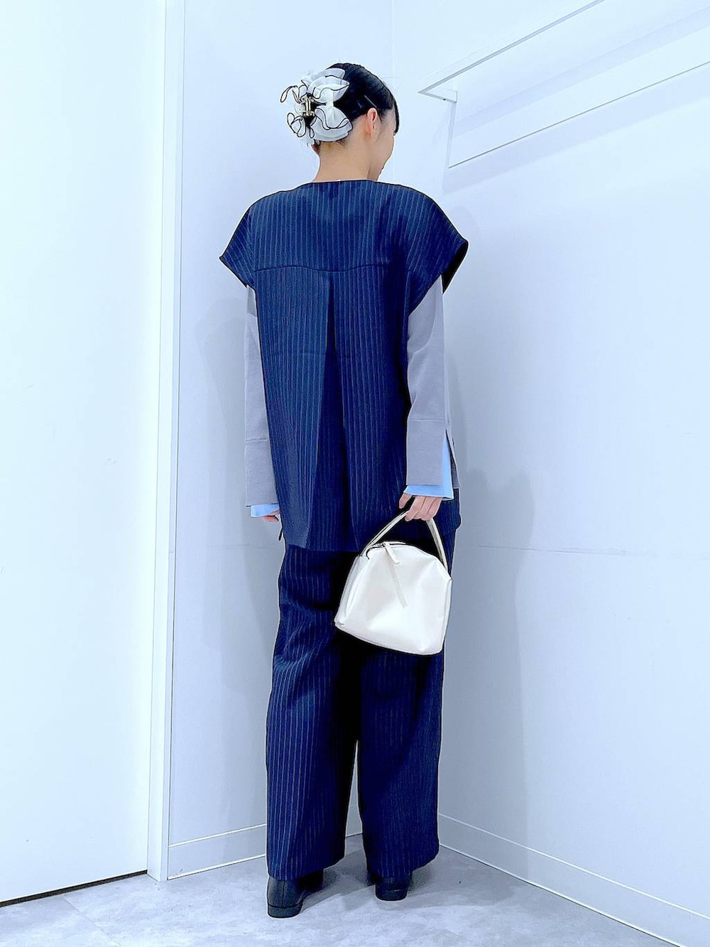 ホワイト系のショルダーバッグ、ブルー系のスラックス、ブルー系のベストを着用したレディースの冬コーディネートの5枚目の写真