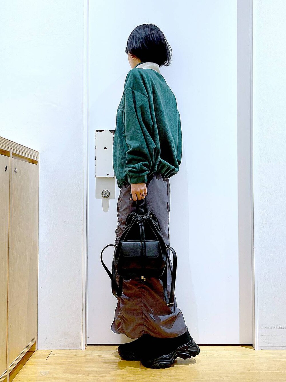 ブラック系のバックパック/リュック、グレー系のスカート、ブラック系のブーツを着用したレディースの冬コーディネートの3枚目の写真