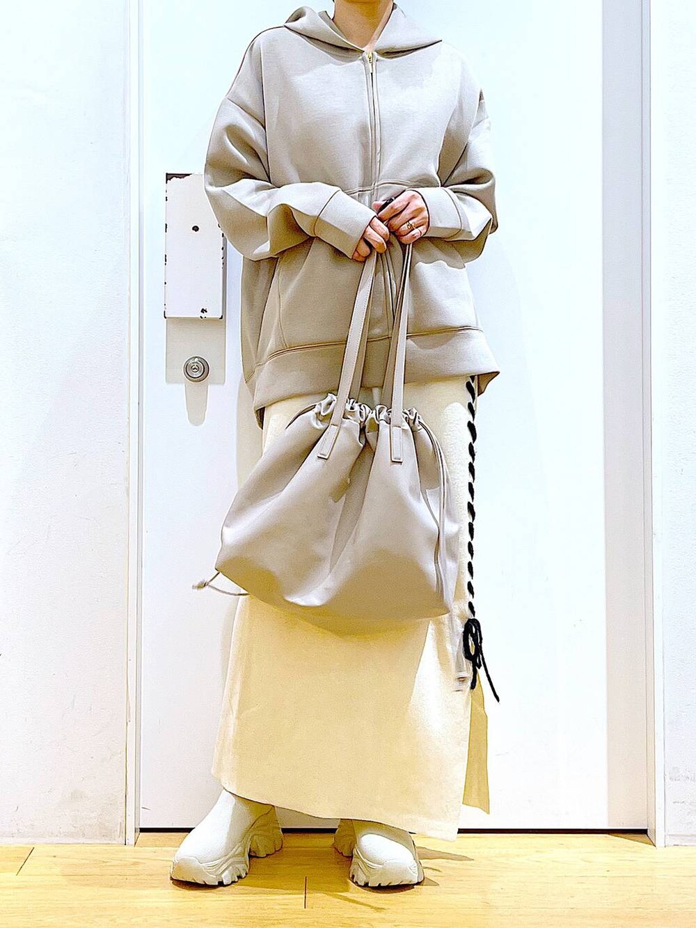 ベージュ系のトートバッグ、ベージュ系のブーツ、ベージュ系のスカートを着用したレディースの秋コーディネートの6枚目の写真