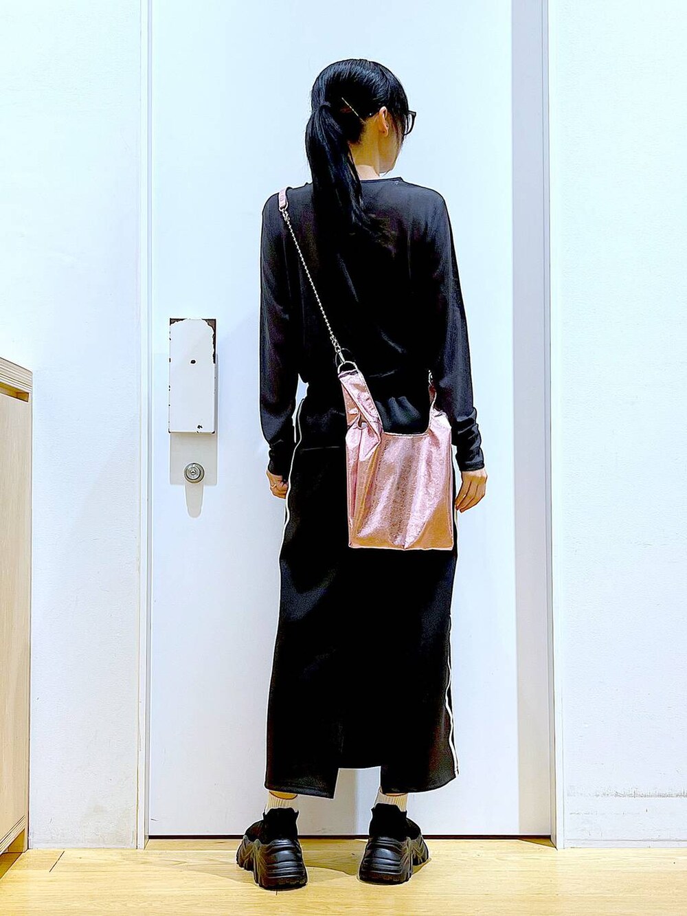 ブラック系のスカート、ピンク系のショルダーバッグ、ブラック系のスニーカーを着用したレディースの春コーディネートの5枚目の写真