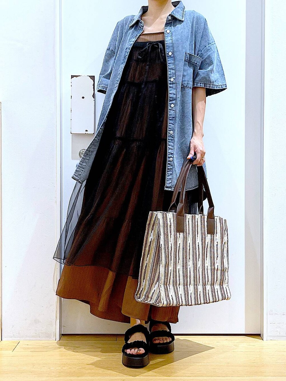 ブラック系のサンダル、ブラウン系のトートバッグ、ブラック系のワンピースを着用したレディースの夏コーディネートの6枚目の写真