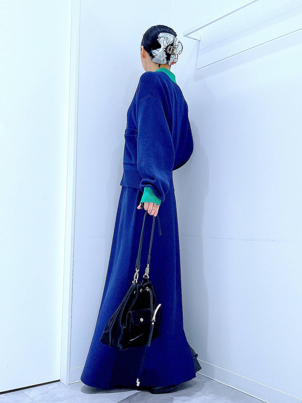 ブラック系のショルダーバッグ、ブラック系のブーツ、ブルー系のスカートを着用したレディースの冬コーディネートの3枚目の写真