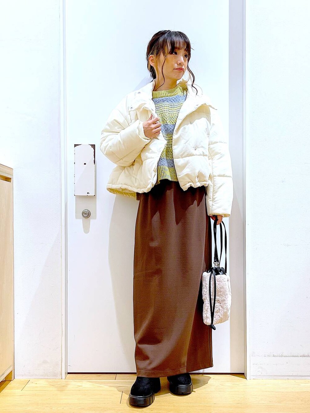 ベージュ系のショルダーバッグ、ブラック系のブーツ、ベージュ系のナイロンジャケットを着用したレディースの冬コーディネートの2枚目の写真