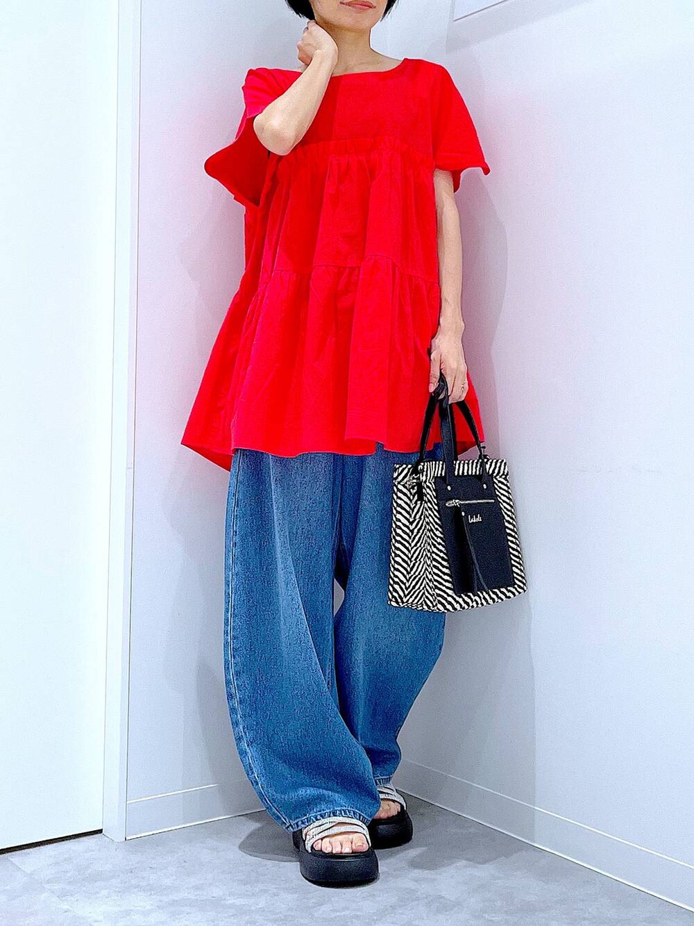 ブルー系のデニムパンツ、ブラック系のショルダーバッグ、シルバー系のサンダルを着用したレディースの夏コーディネートの6枚目の写真