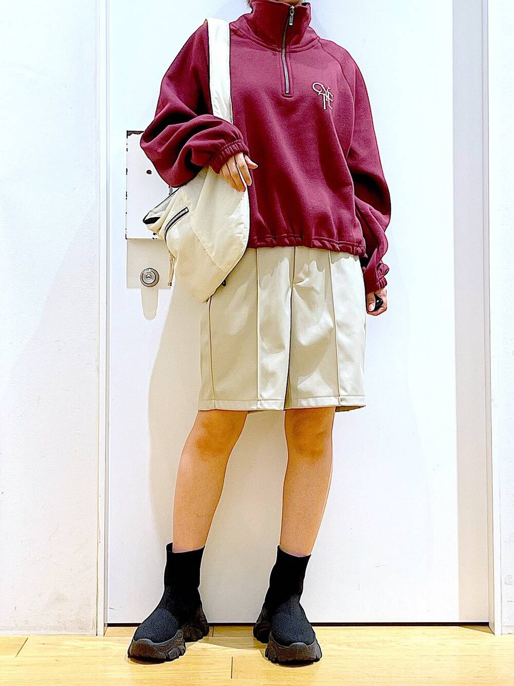 ホワイト系のショルダーバッグ、ブラック系のブーツ、レッド系のスウェットを着用したレディースの冬コーディネートの6枚目の写真