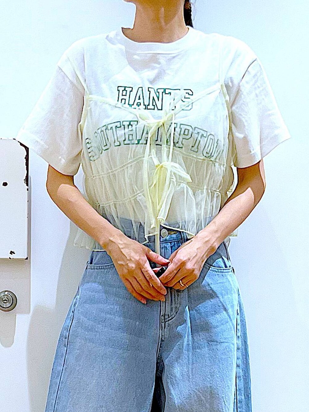 ブルー系のデニムパンツ、イエロー系のキャミソール、ホワイト系のトートバッグを着用したレディースの春コーディネートの7枚目の写真