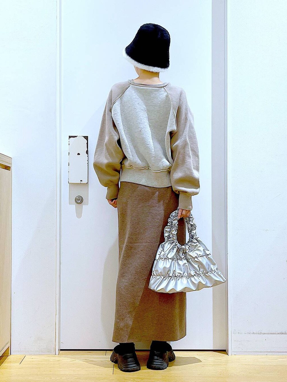 ブラック系のブーツ、ブラウン系のスカート、シルバー系のショルダーバッグを着用したレディースの冬コーディネートの5枚目の写真