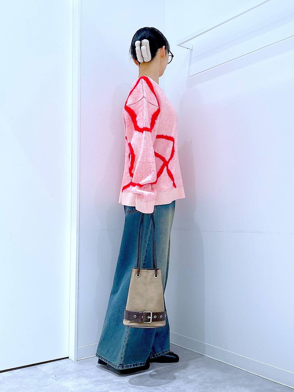 ブルー系のデニムパンツ、ブラック系のブーツ、ベージュ系のハンドバッグを着用したレディースの冬コーディネートの4枚目の写真