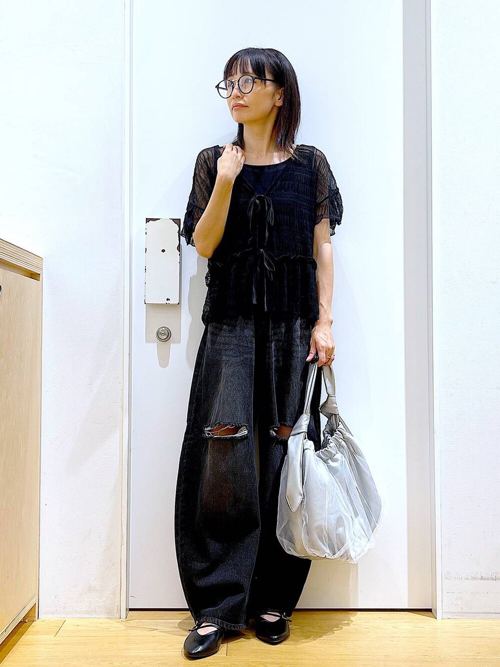 シルバー系のトートバッグ、ブラック系のデニムパンツ、ブラック系のカーディガン/ボレロを着用したレディースの秋コーディネートの2枚目の写真