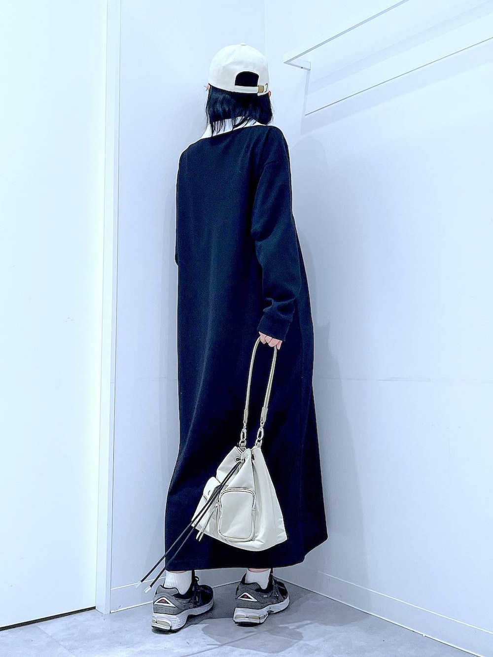 ホワイト系のショルダーバッグ、ブラック系のワンピース、ホワイト系のキャップを着用したレディースの春コーディネートの5枚目の写真