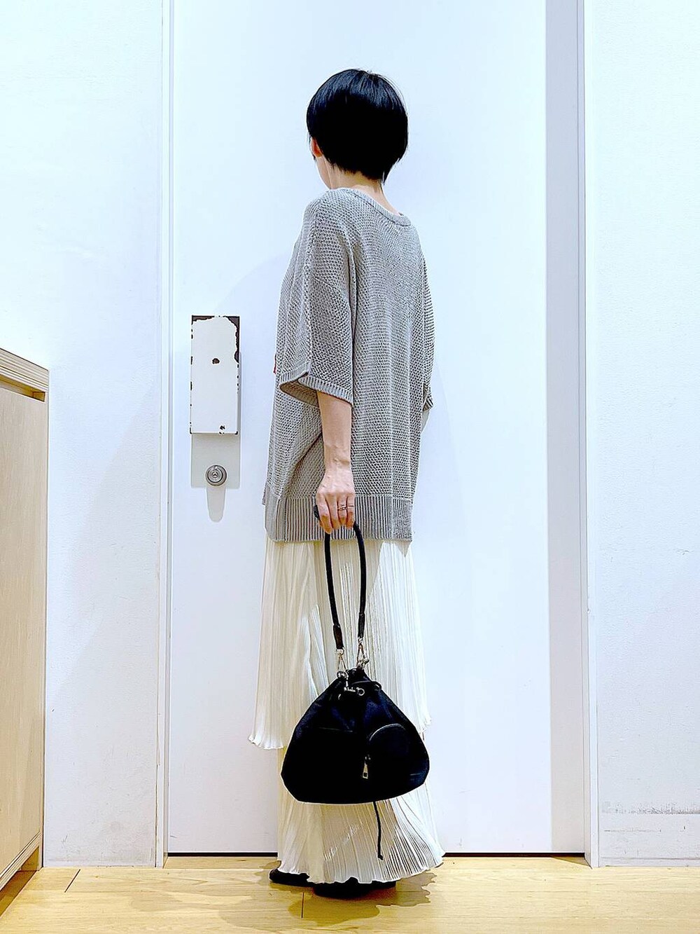 ブラック系のパンプス、ホワイト系のスカート、グレー系のニット/セーターを着用したレディースの春コーディネートの3枚目の写真