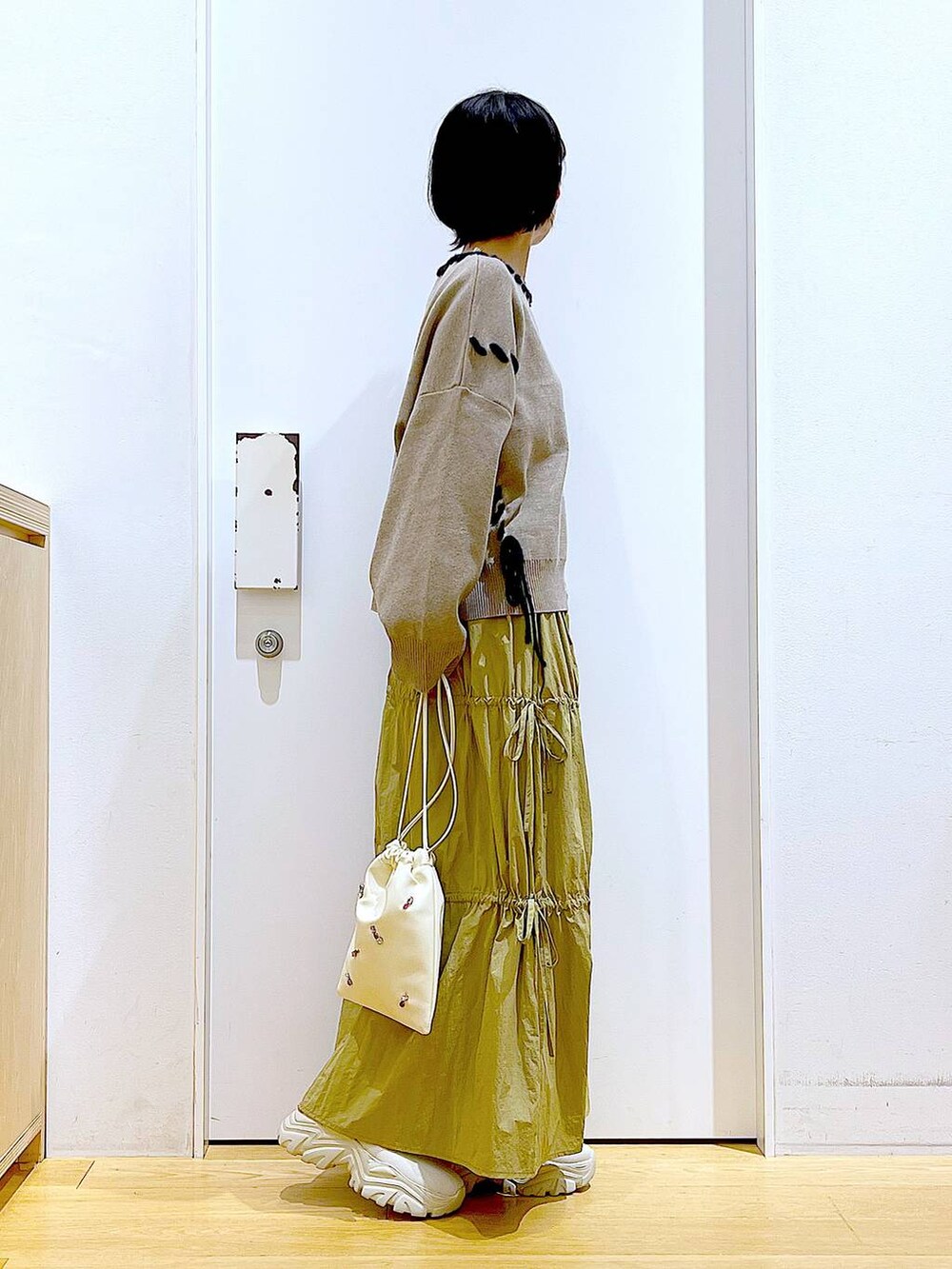 ホワイト系のショルダーバッグ、イエロー系のスカート、ベージュ系のブーツを着用したレディースの秋コーディネートの4枚目の写真