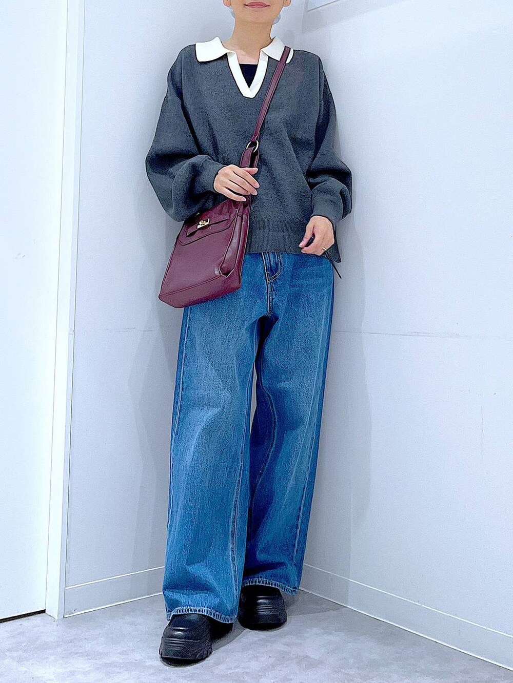 ブルー系のデニムパンツ、レッド系のショルダーバッグ、グレー系のニット/セーターを着用したレディースの秋コーディネートの6枚目の写真