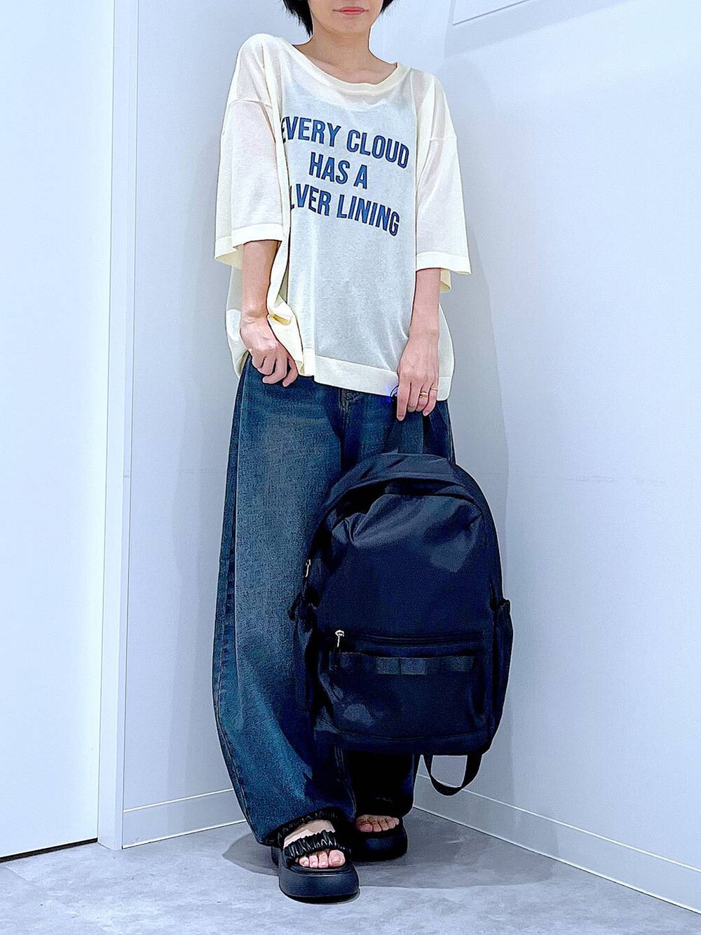 ブルー系のデニムパンツ、ブラック系のバックパック/リュック、ブラック系のサンダルを着用したレディースの夏コーディネートの6枚目の写真