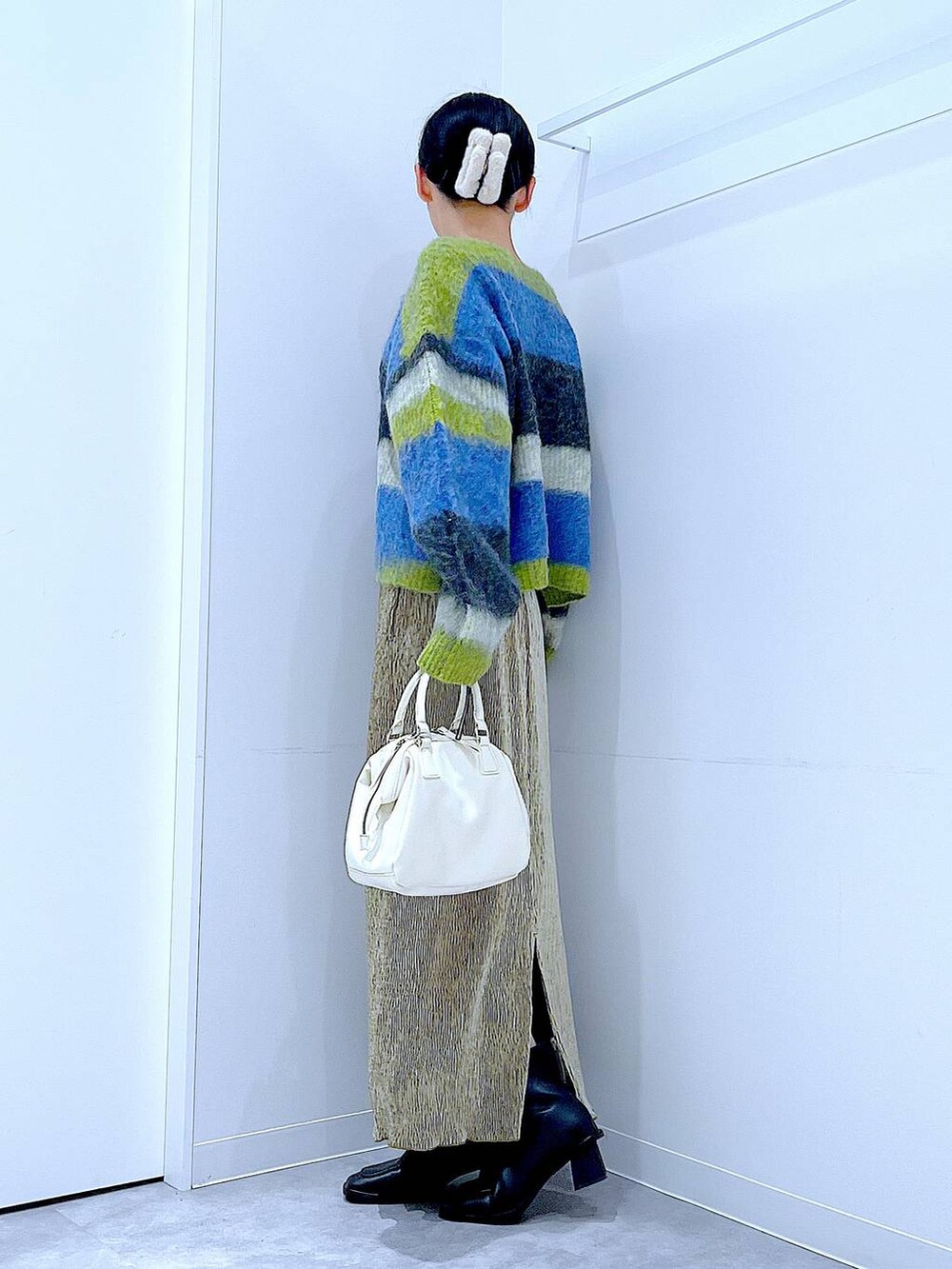 ブラック系のブーツ、ホワイト系のショルダーバッグ、ブルー系のニット/セーターを着用したレディースの冬コーディネートの3枚目の写真