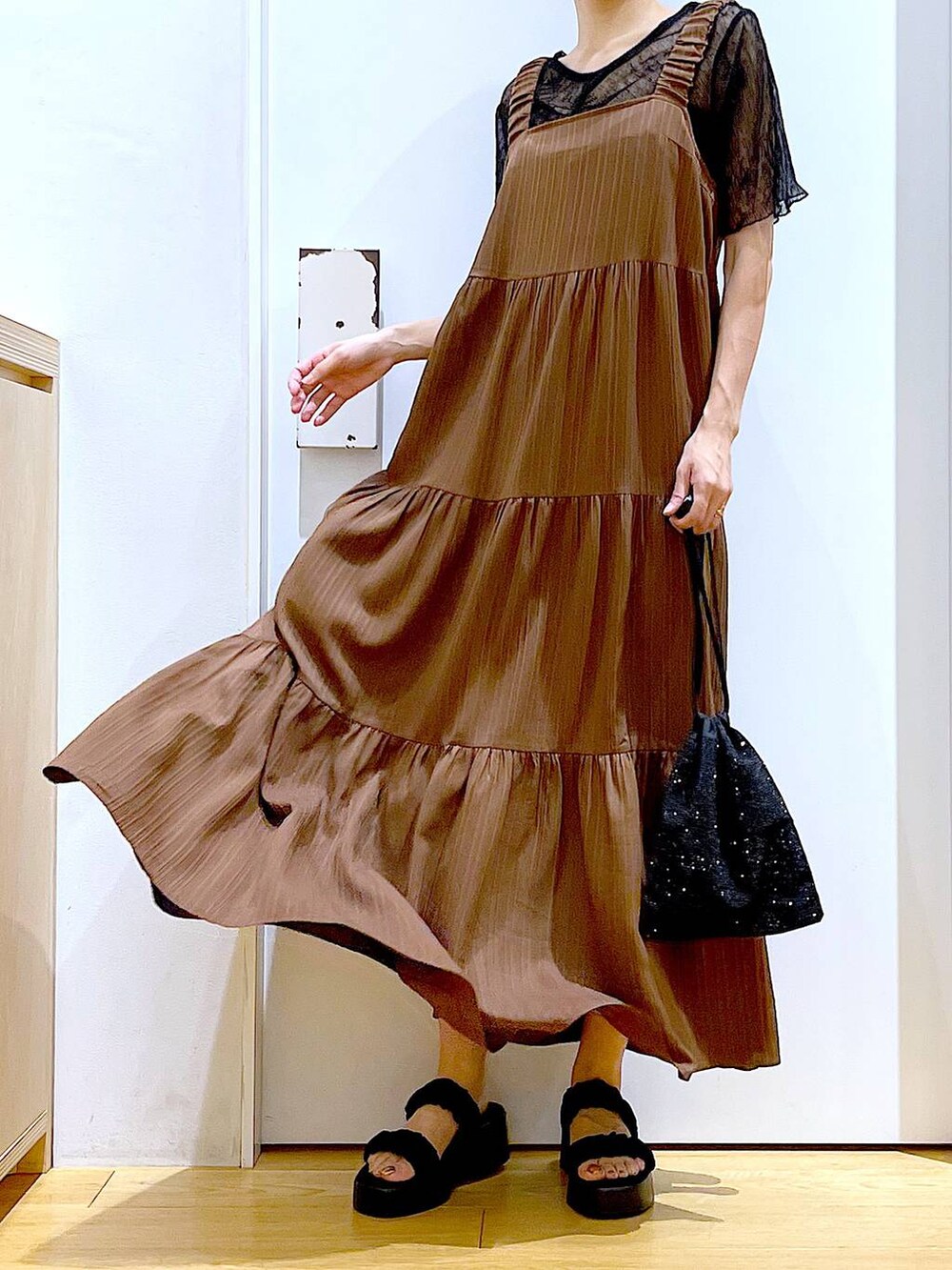 ブラック系のサンダル、ブラック系のショルダーバッグ、ベージュ系のワンピースを着用したレディースの夏コーディネートの6枚目の写真