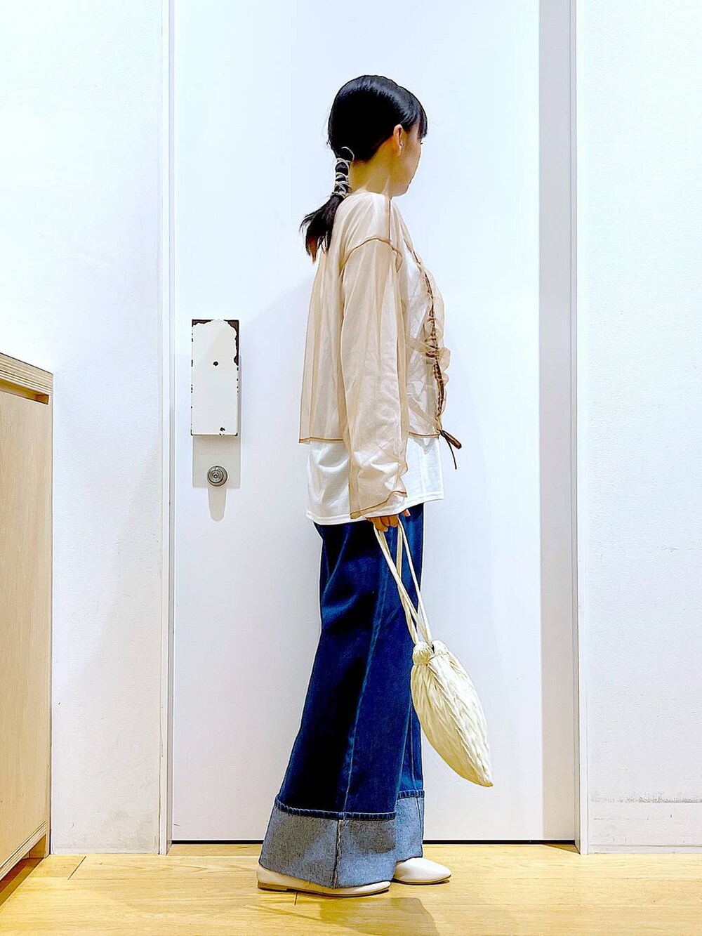 ホワイト系のショルダーバッグ、ホワイト系のパンプス、ブルー系のデニムパンツを着用したレディースの秋コーディネートの4枚目の写真