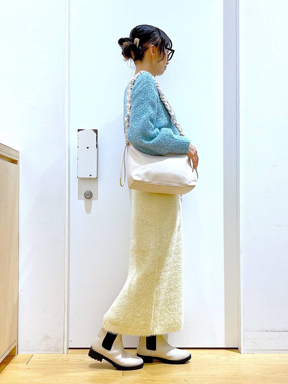 ホワイト系のショルダーバッグ、ベージュ系のブーツ、ホワイト系のスカートを着用したレディースの冬コーディネートの4枚目の写真