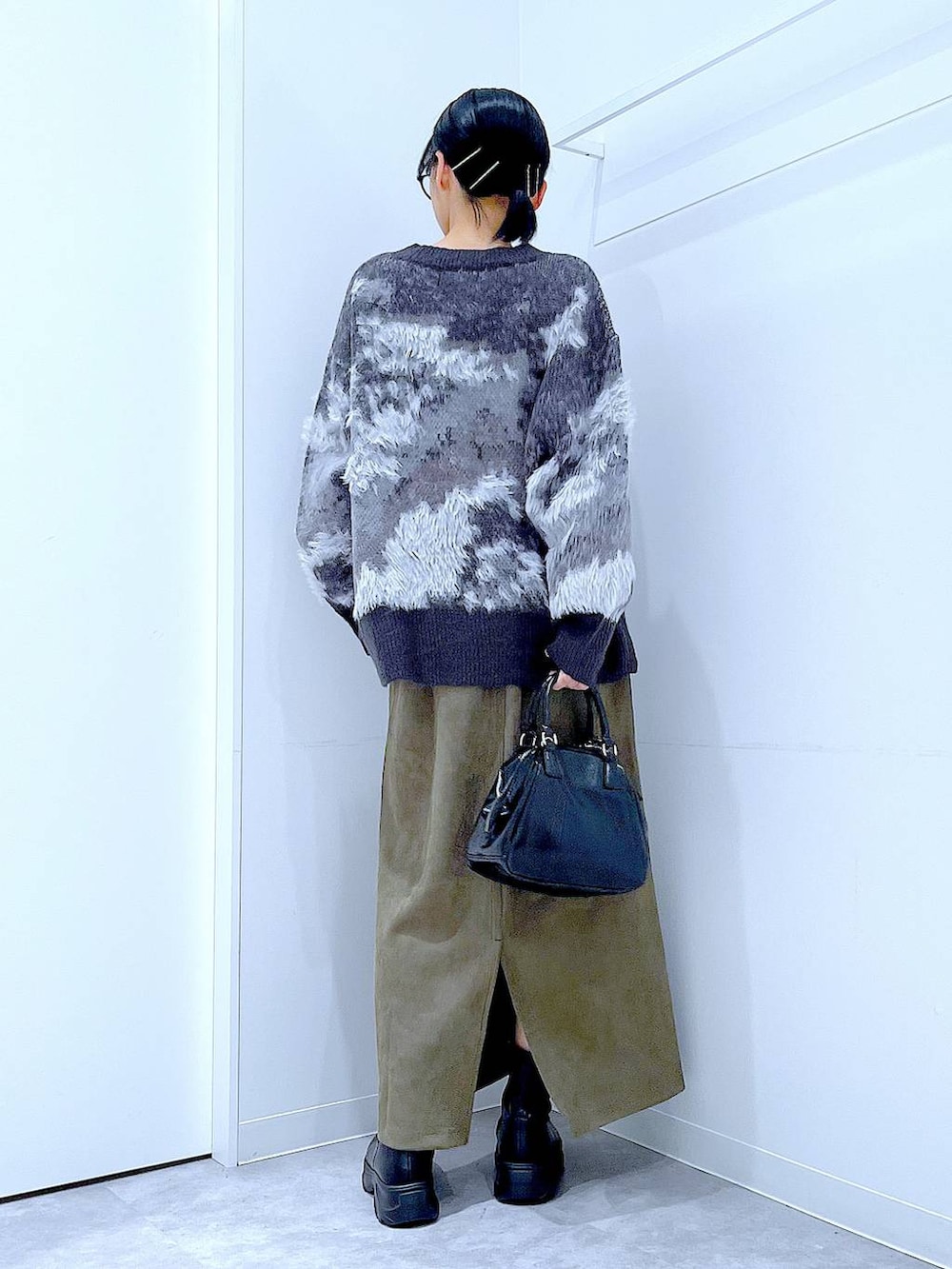 ブラック系のブーツ、ブラック系のニット/セーター、ブラック系のショルダーバッグを着用したレディースの冬コーディネートの5枚目の写真