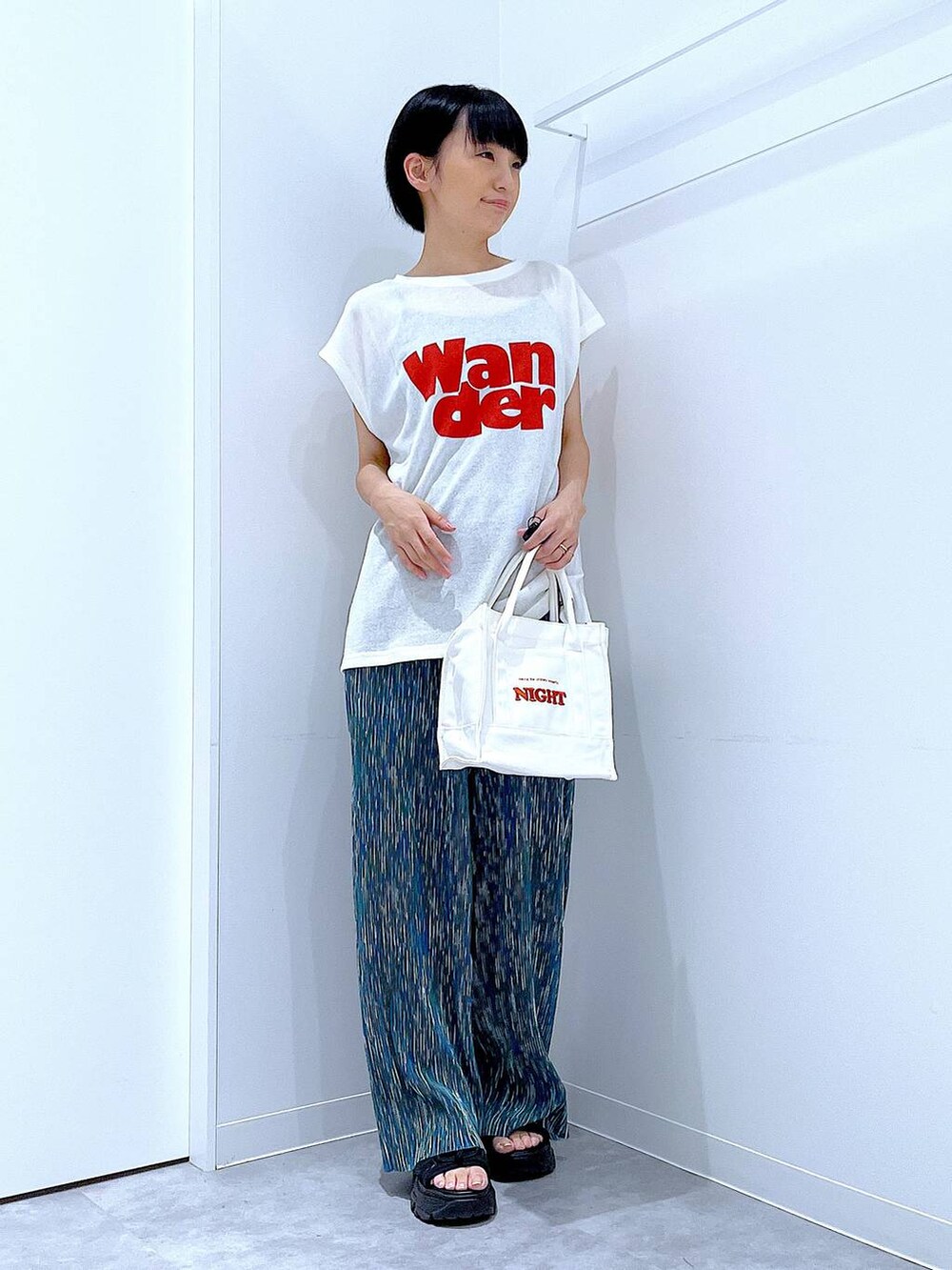 ブラック系のスニーカー、ホワイト系のTシャツ/カットソー、ホワイト系のトートバッグを着用したレディースの夏コーディネートの2枚目の写真