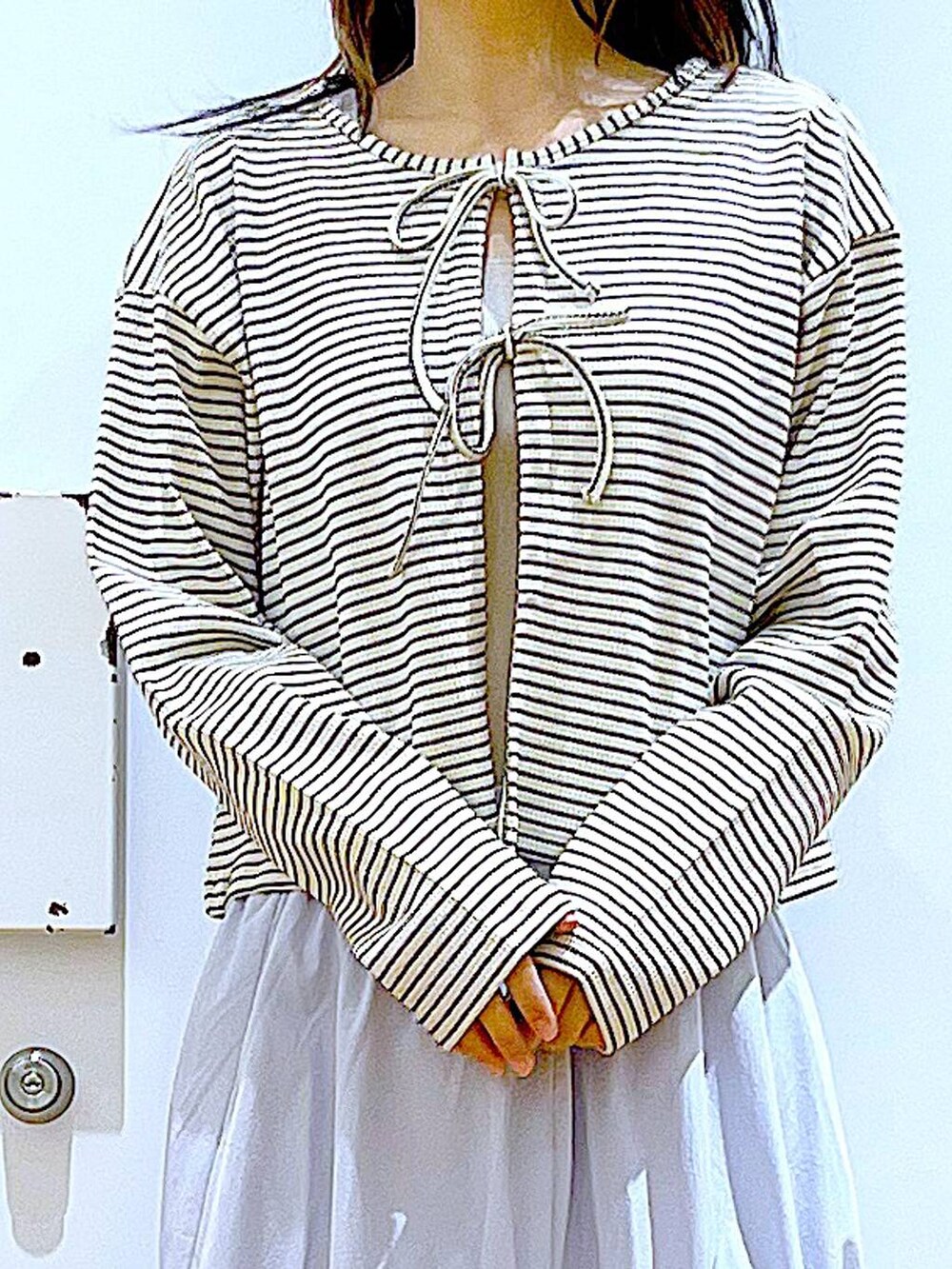 ブラック系のトートバッグ、ブルー系のスカート、イエロー系のニット/セーターを着用したレディースの春コーディネートの7枚目の写真