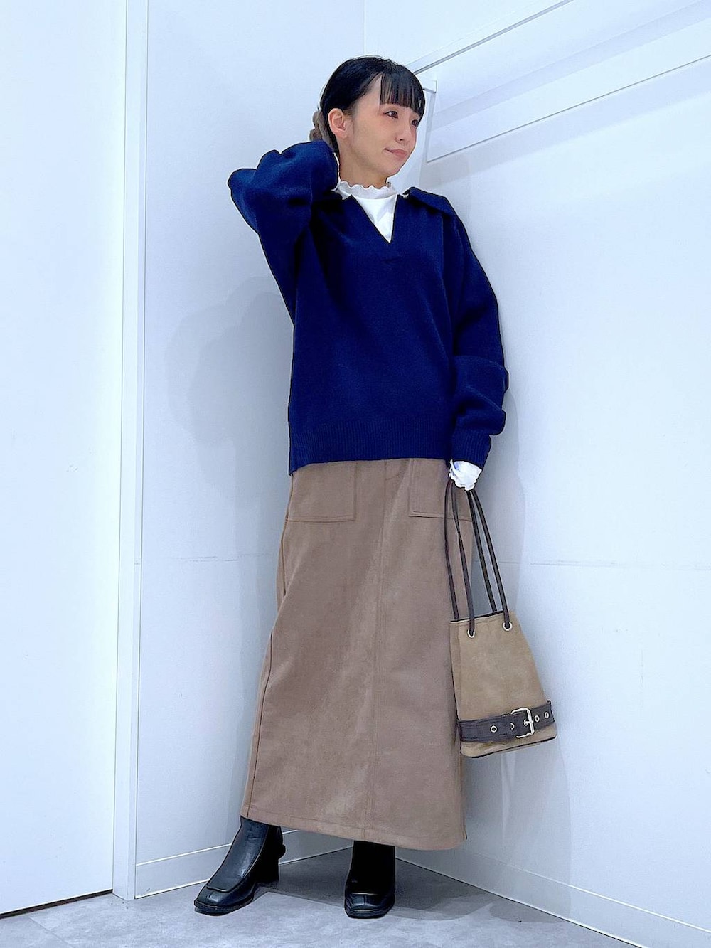 ブラック系のブーツ、ブラウン系のスカート、ベージュ系のハンドバッグを着用したレディースの冬コーディネートの2枚目の写真