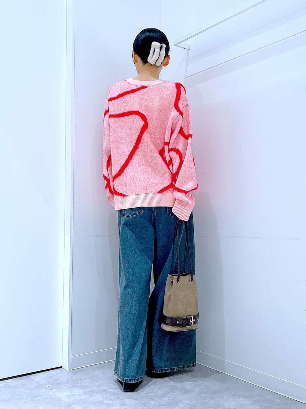 ブルー系のデニムパンツ、ブラック系のブーツ、ベージュ系のハンドバッグを着用したレディースの冬コーディネートの5枚目の写真