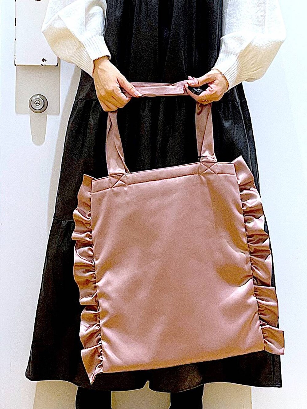 ブラック系のブーツ、ブラック系のワンピース、ピンク系のトートバッグを着用したレディースの冬コーディネートの9枚目の写真