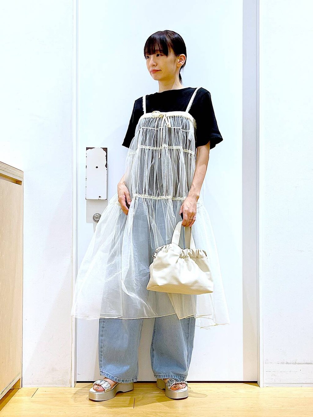 ブルー系のデニムパンツ、ホワイト系のショルダーバッグ、ブラック系のTシャツ/カットソーを着用したレディースの夏コーディネートの2枚目の写真