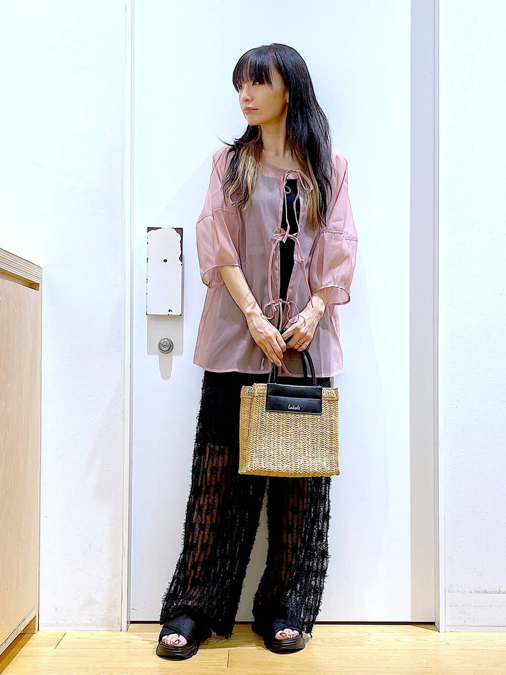 ブラック系のサンダル、ブラック系のニット/セーター、ベージュ系のショルダーバッグを着用したレディースの夏コーディネートの2枚目の写真