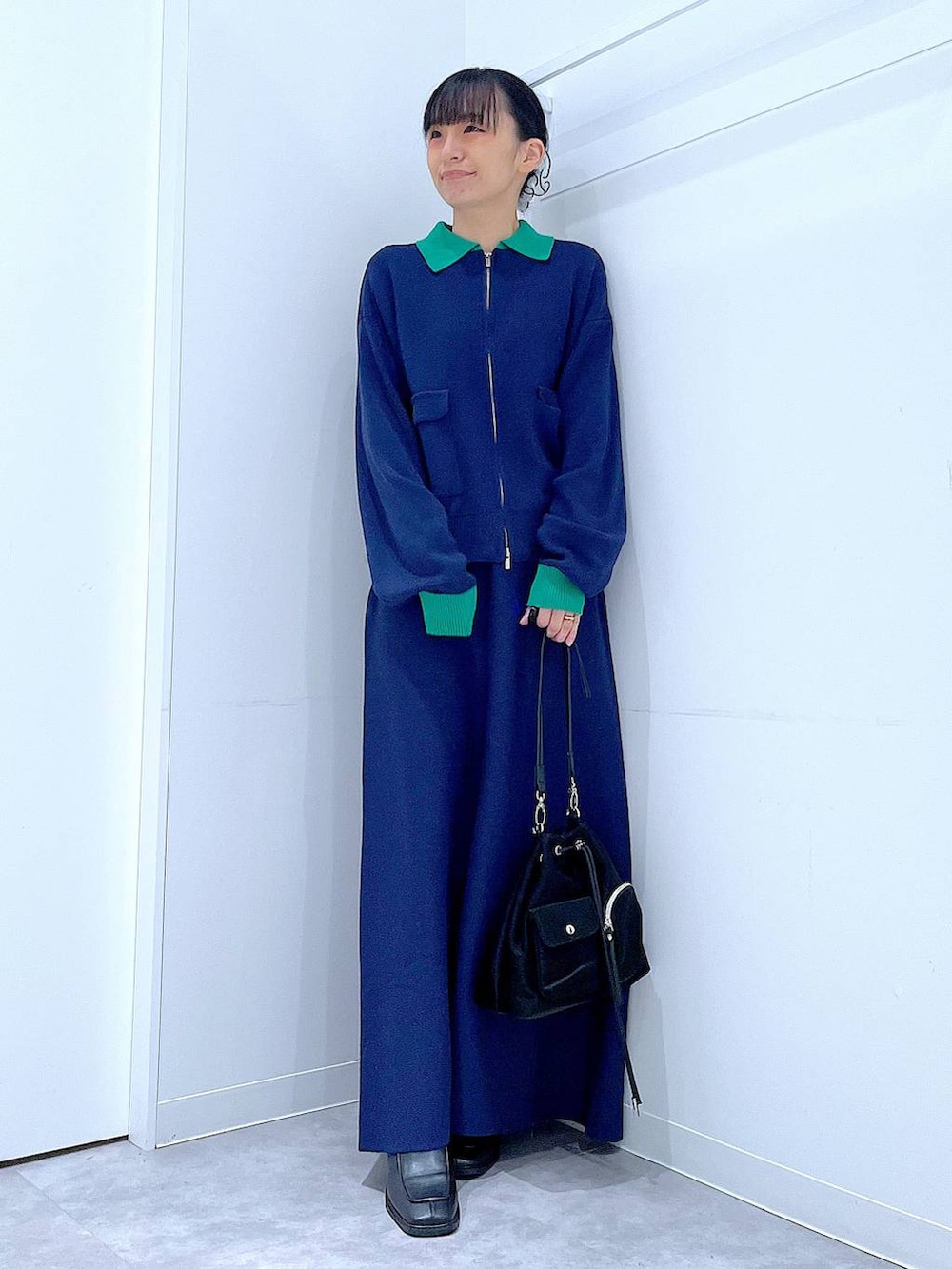 ブラック系のショルダーバッグ、ブラック系のブーツ、ブルー系のスカートを着用したレディースの冬コーディネートの2枚目の写真