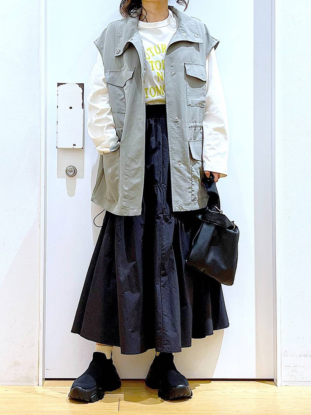 ブラック系のショルダーバッグ、ブラック系のスニーカー、ブラック系のスカートを着用したレディースの春コーディネートの6枚目の写真