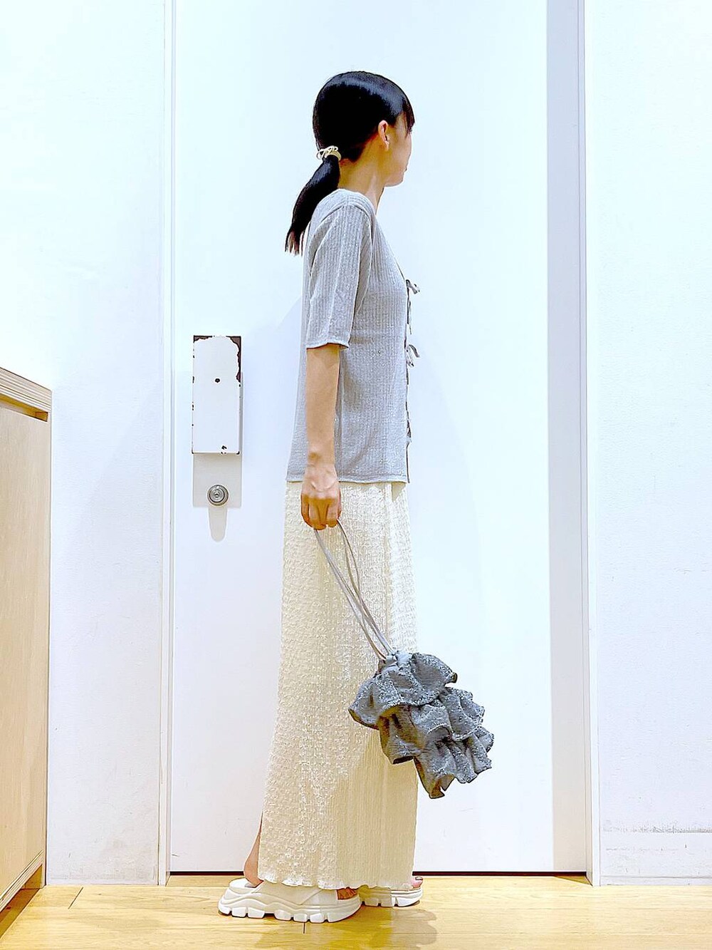 シルバー系のショルダーバッグ、ホワイト系のニット/セーター、ホワイト系のサンダルを着用したレディースの夏コーディネートの4枚目の写真