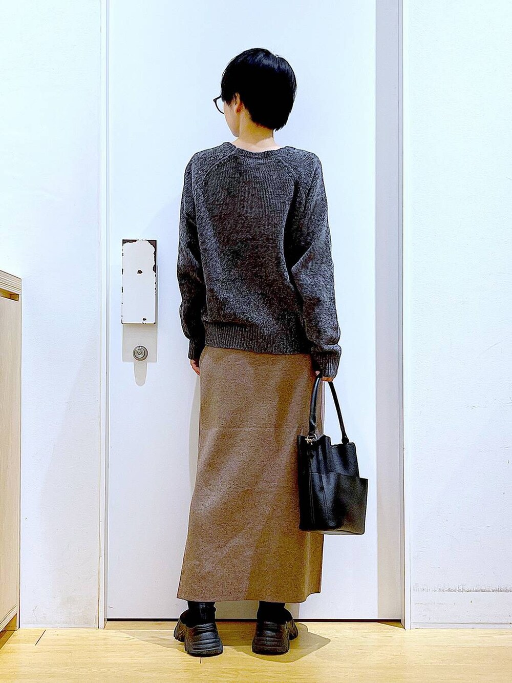 ブラック系のブーツ、ブラック系のショルダーバッグ、ブラウン系のスカートを着用したレディースの冬コーディネートの5枚目の写真