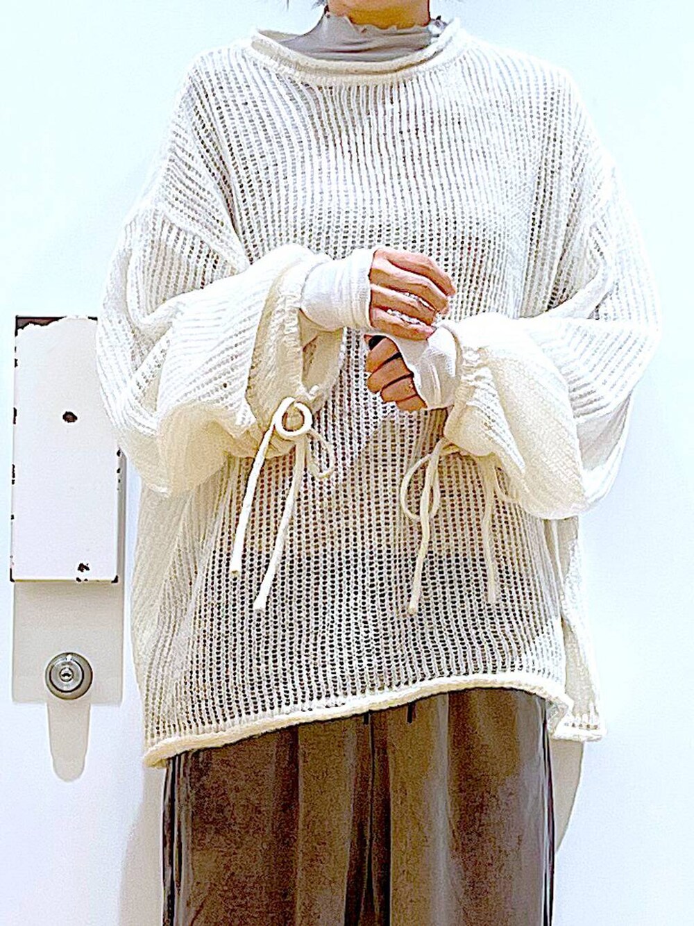 ブラック系のショルダーバッグ、ブラック系のブーツ、ホワイト系のニット/セーターを着用したレディースの冬コーディネートの7枚目の写真