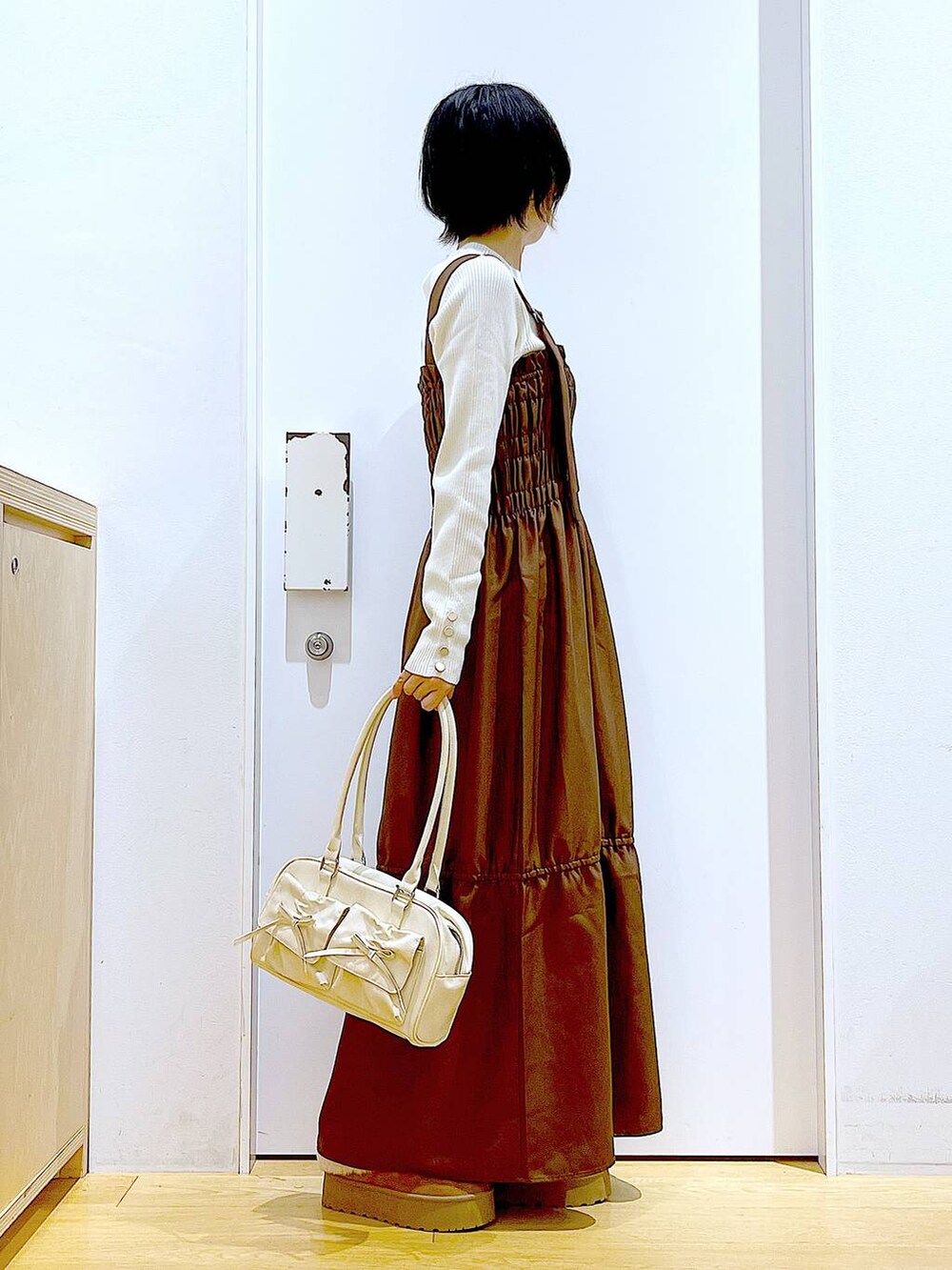 ホワイト系のニット/セーター、ホワイト系のハンドバッグ、ベージュ系のスリッポンを着用したレディースの冬コーディネートの4枚目の写真