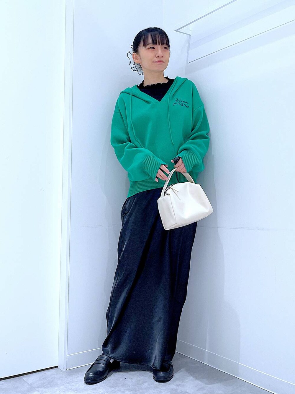ブラック系のTシャツ/カットソー、ホワイト系のショルダーバッグ、グリーン系のニット/セーターを着用したレディースの春コーディネートの2枚目の写真