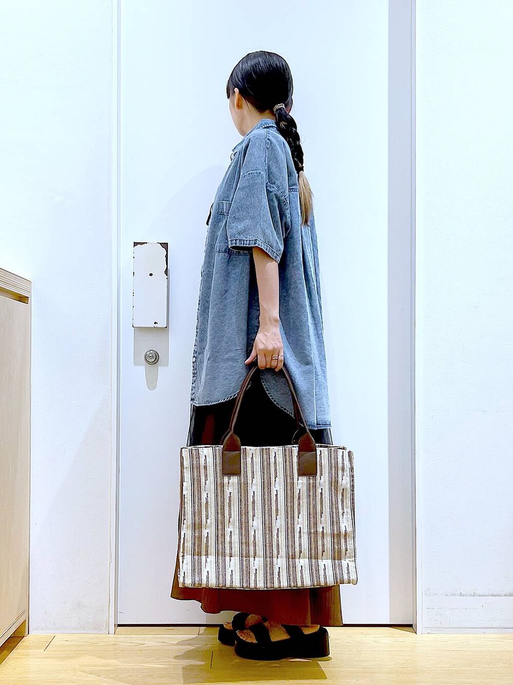 ブラック系のサンダル、ブラウン系のトートバッグ、ブラック系のワンピースを着用したレディースの夏コーディネートの3枚目の写真