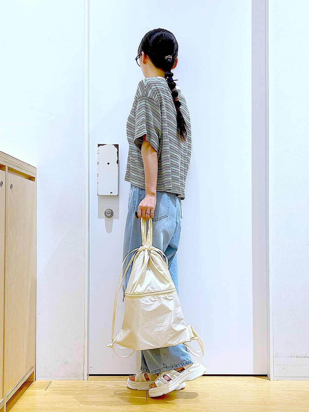 ホワイト系のバックパック/リュック、ホワイト系のサンダル、ブルー系のデニムパンツを着用したレディースの夏コーディネートの3枚目の写真