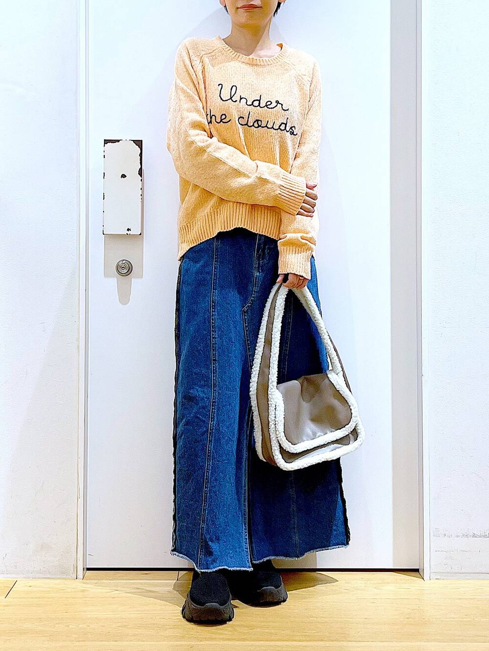 ブルー系のデニムスカート、ベージュ系のショルダーバッグ、ブラック系のブーツを着用したレディースの冬コーディネートの6枚目の写真