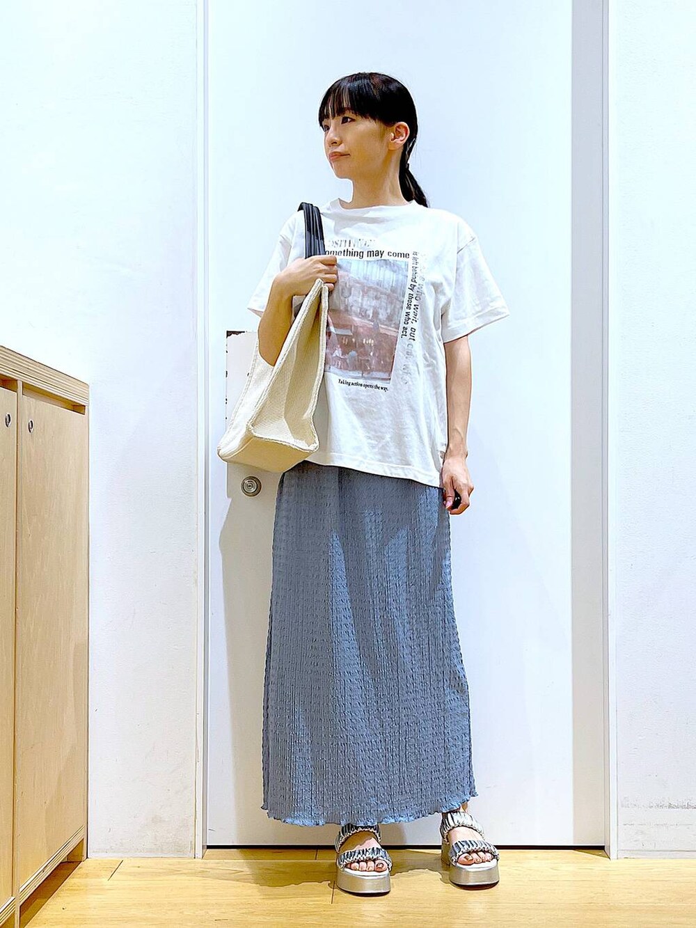 シルバー系のサンダル、ブルー系のスカート、ホワイト系のトートバッグを着用したレディースの夏コーディネートの2枚目の写真