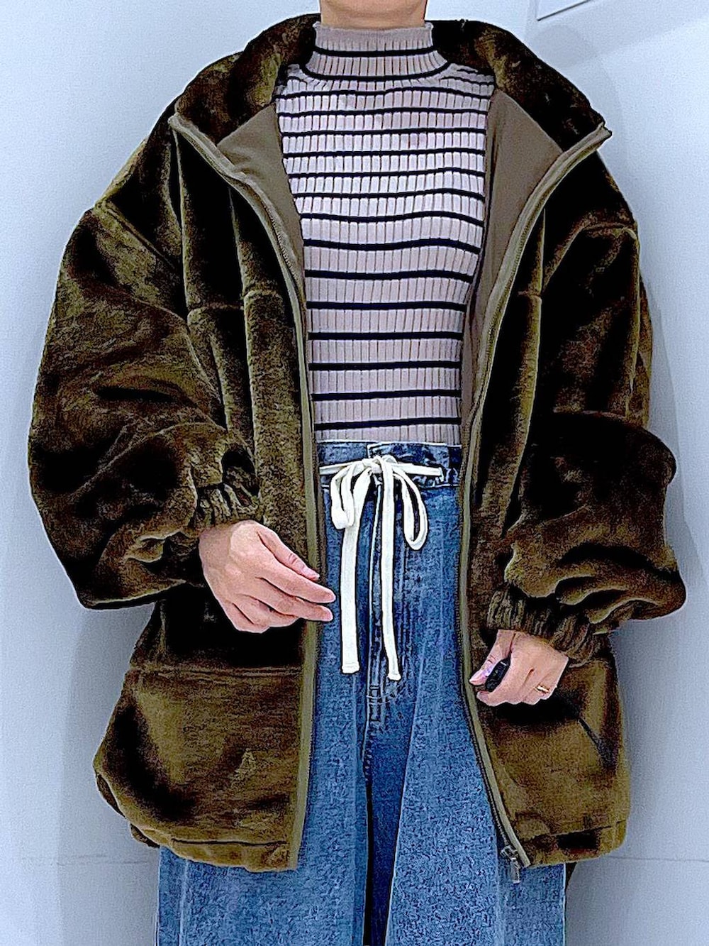 グリーン系のブルゾン、その他のニット/セーター、ブルー系のデニムパンツを着用したレディースの冬コーディネートの7枚目の写真