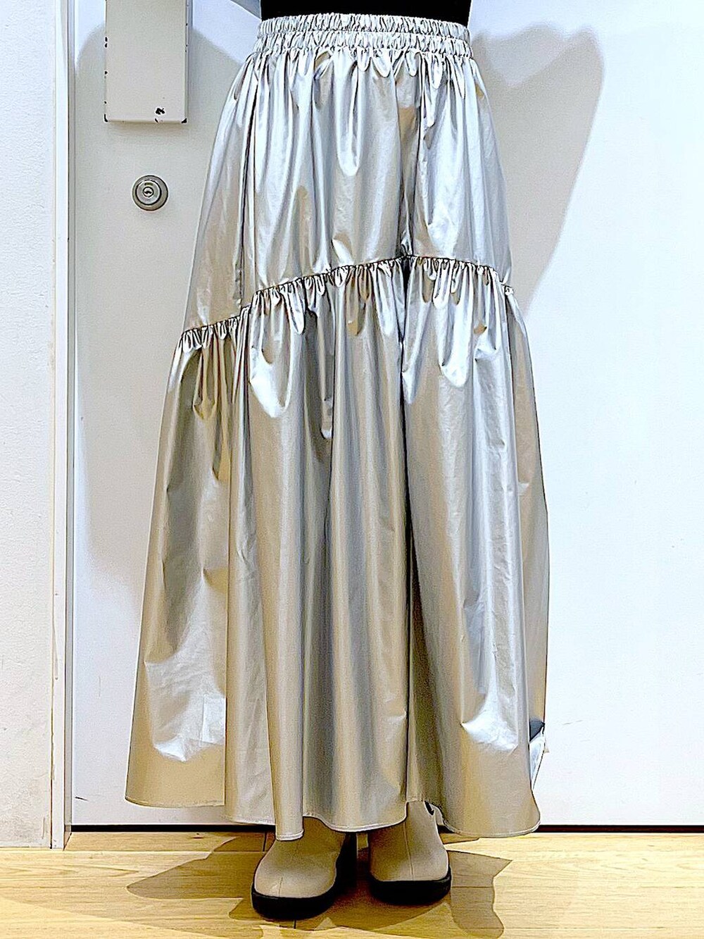 ブルー系のスウェット、シルバー系のスカート、ベージュ系のブーツを着用したレディースの春コーディネートの8枚目の写真