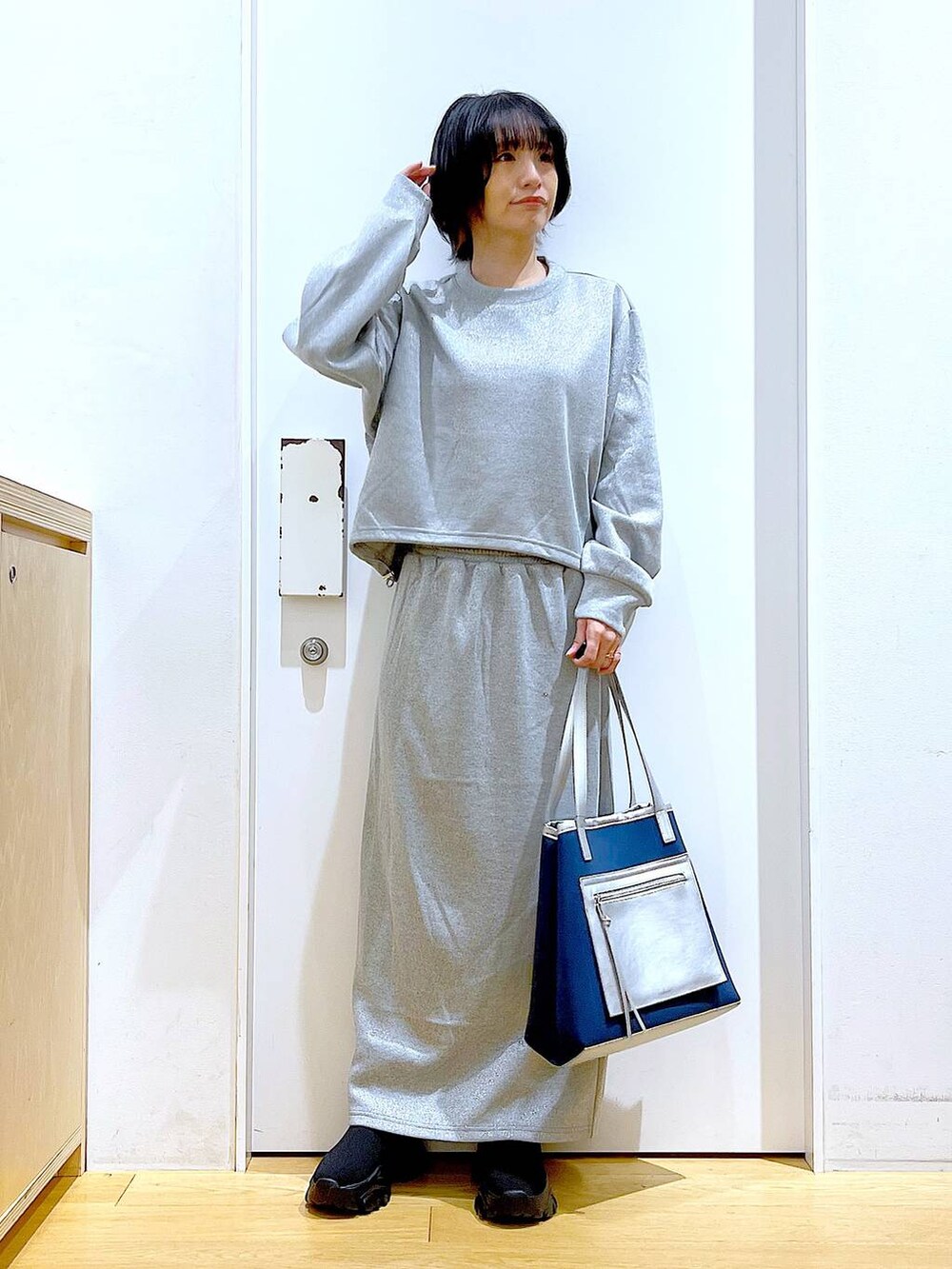 ブラック系のブーツ、ブルー系のトートバッグ、グレー系のスウェットを着用したレディースの冬コーディネートの2枚目の写真