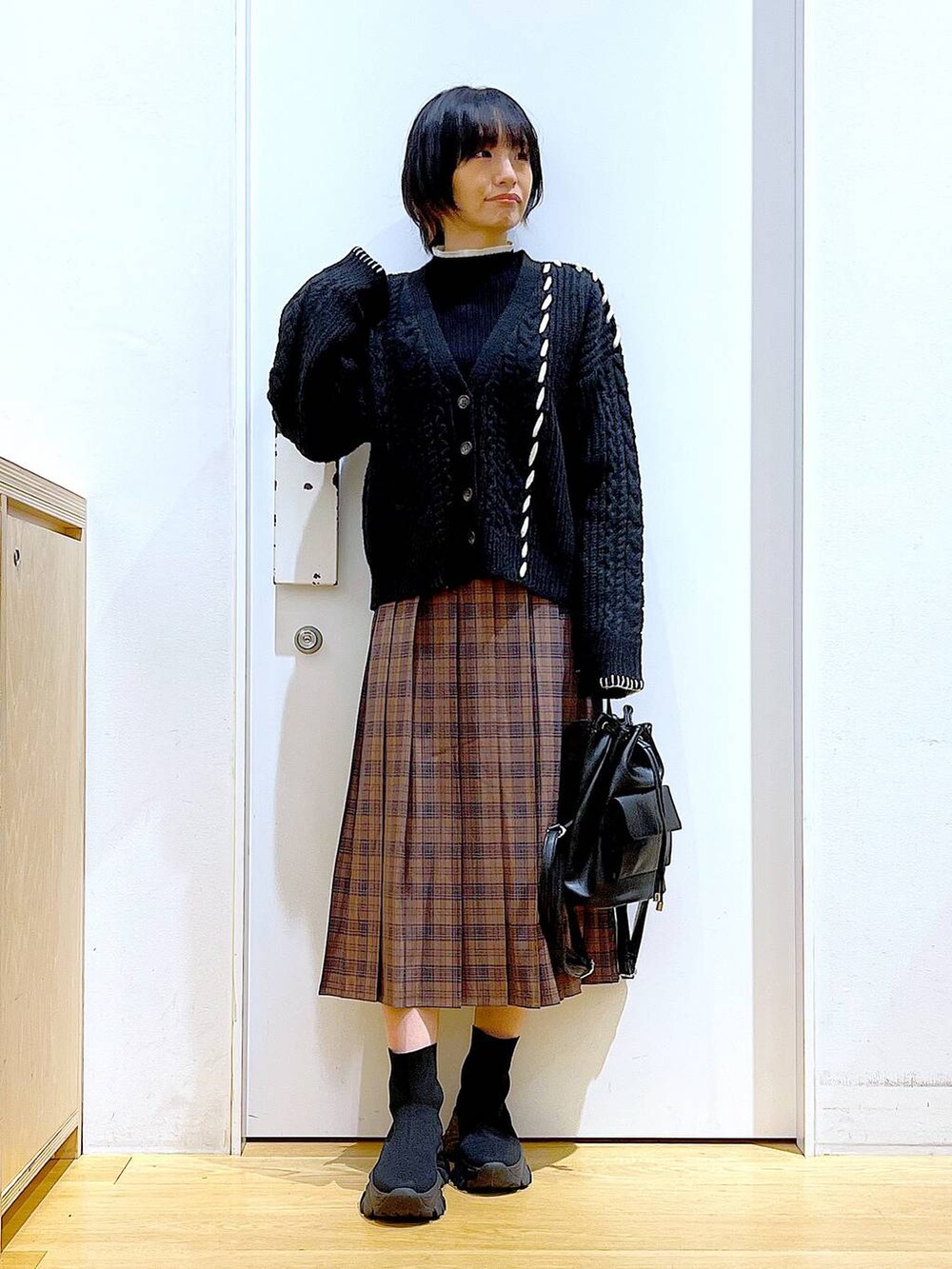 ブラック系のニット/セーター、ブラック系のバックパック/リュック、ブラック系のブーツを着用したレディースの冬コーディネートの2枚目の写真