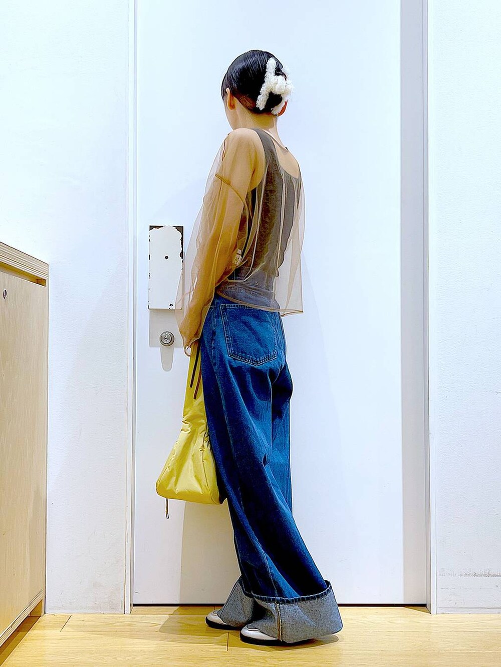 イエロー系のハンドバッグ、シルバー系のローファー、ブルー系のデニムパンツを着用したレディースの秋コーディネートの3枚目の写真