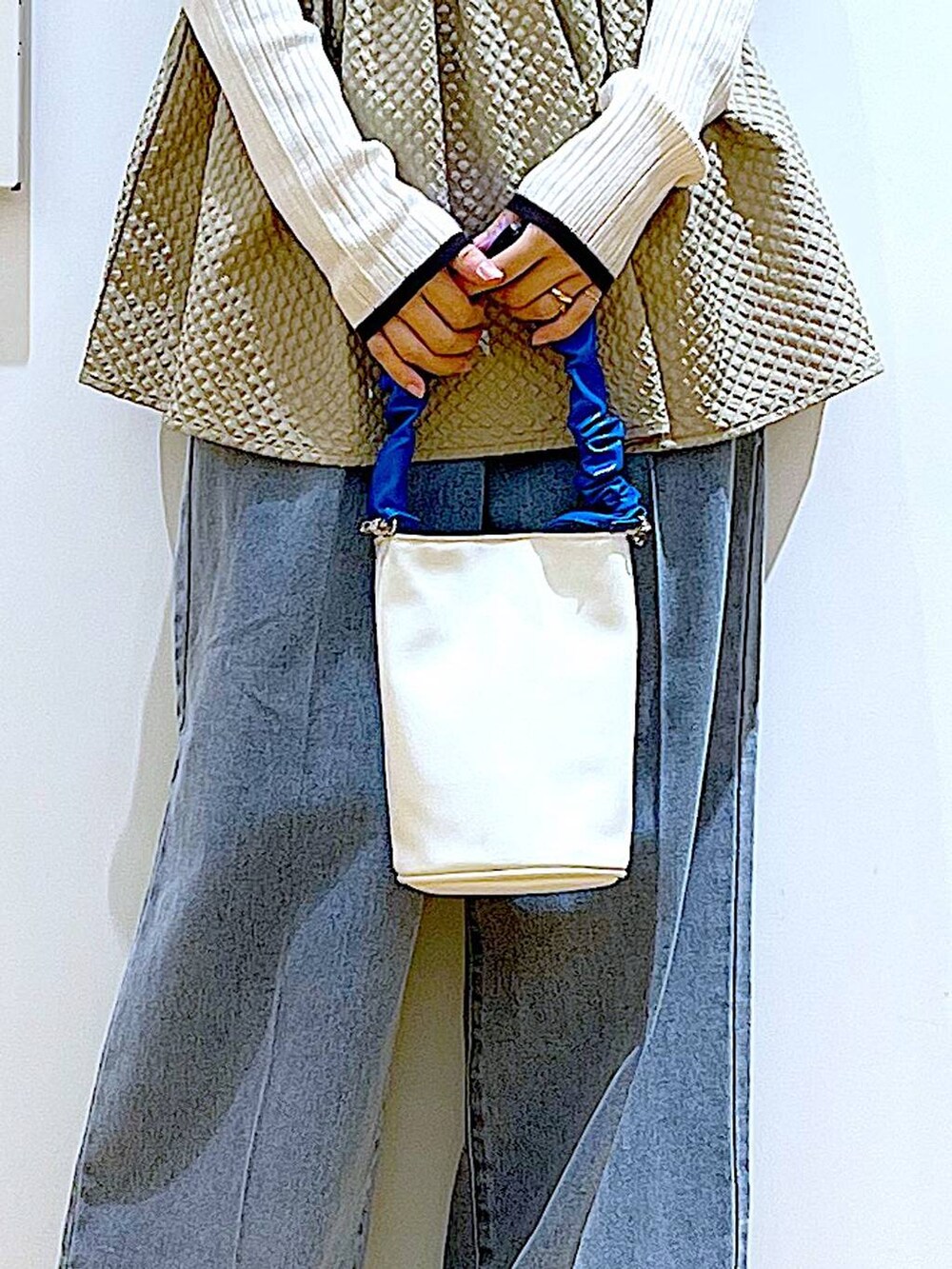 ブルー系のショルダーバッグ、ブルー系のデニムパンツ、ベージュ系のニット/セーターを着用したレディースの春コーディネートの9枚目の写真