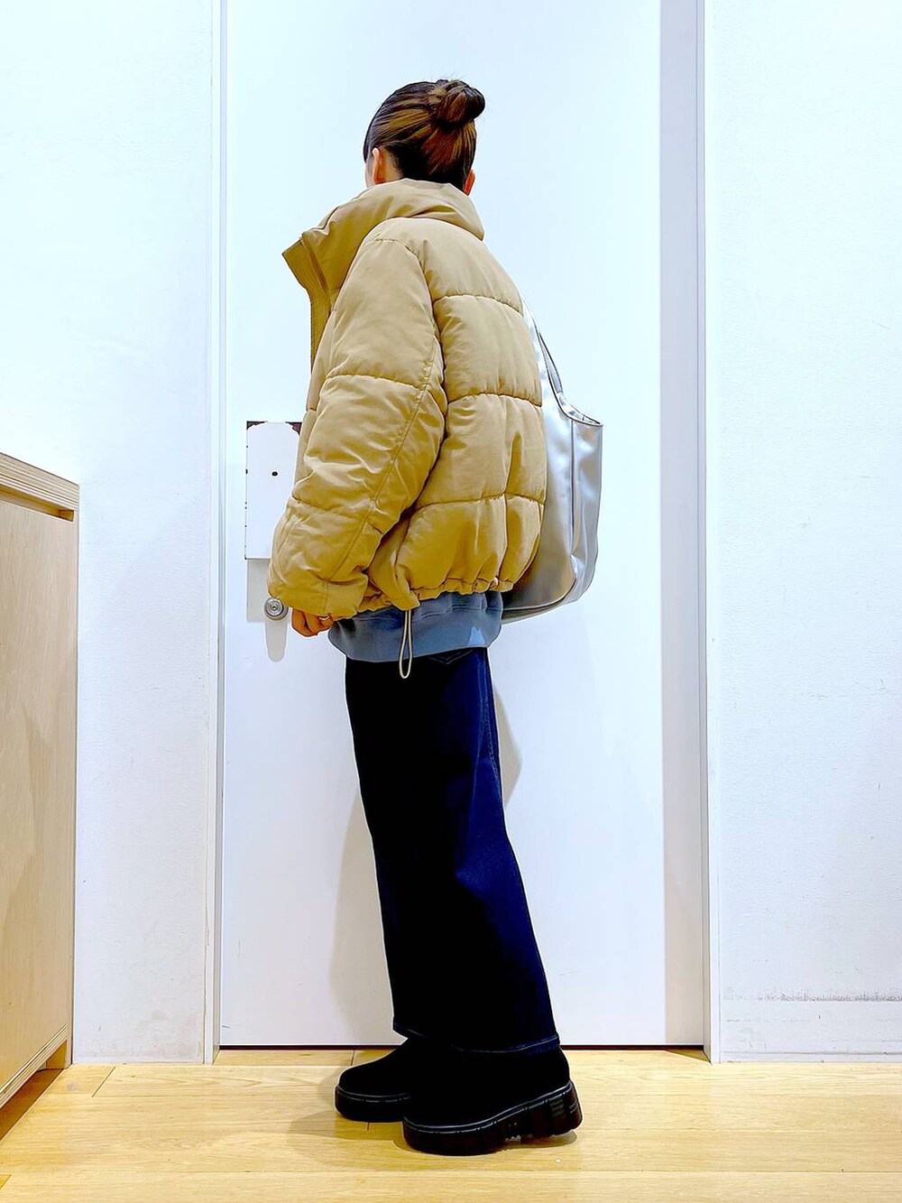 シルバー系のトートバッグ、ベージュ系のナイロンジャケット、ブルー系のデニムスカートを着用したレディースの冬コーディネートの3枚目の写真