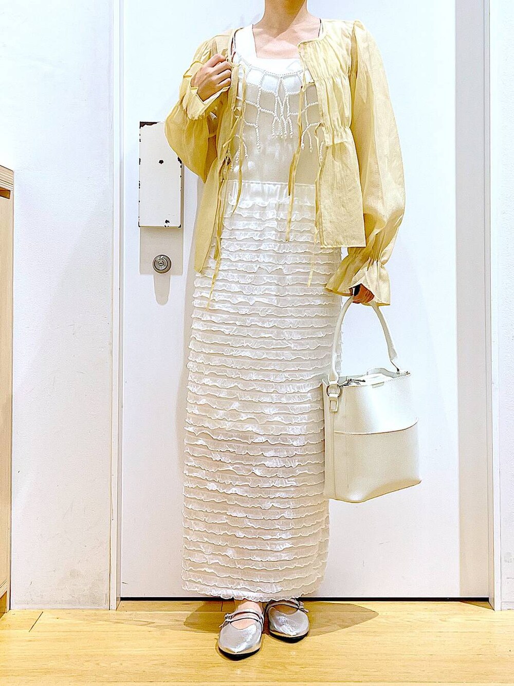ホワイト系のベスト、ホワイト系のショルダーバッグ、ホワイト系のスカートを着用したレディースの秋コーディネートの6枚目の写真