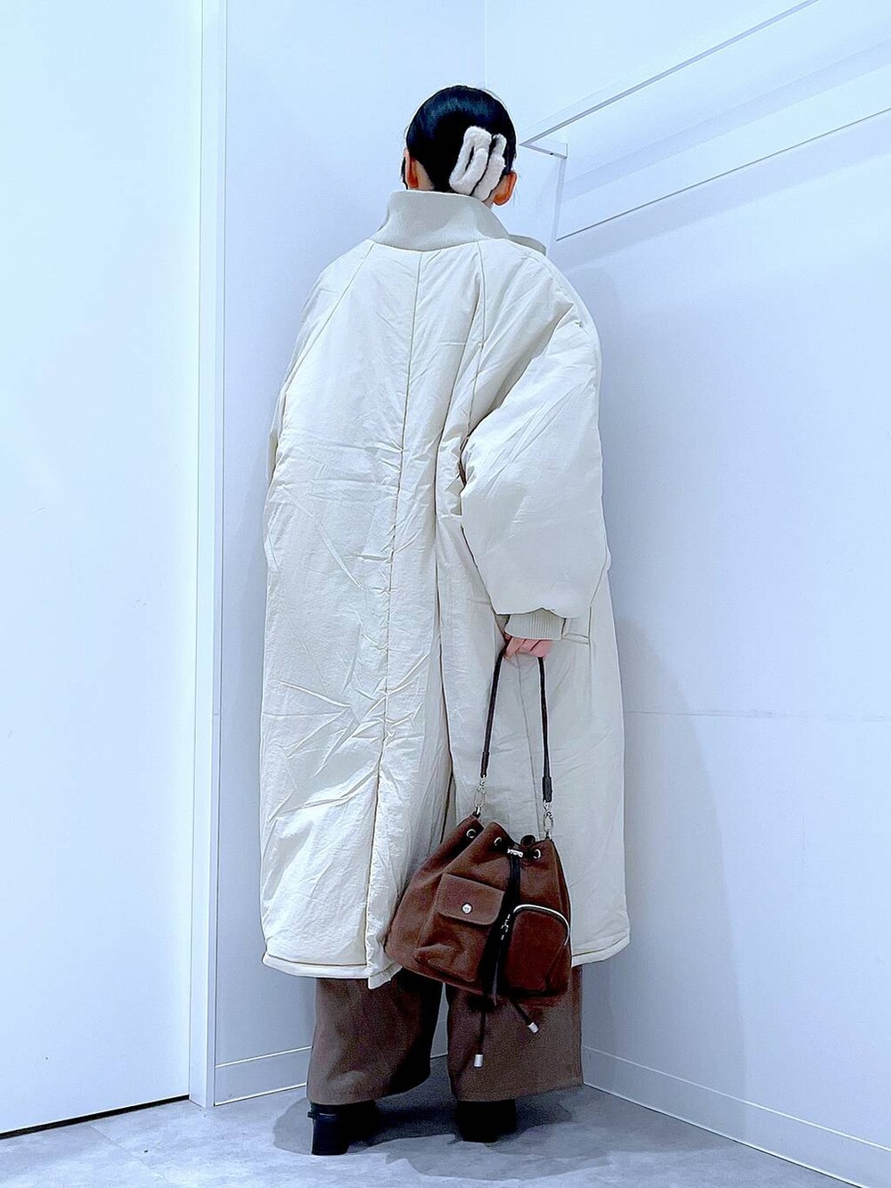 ホワイト系のブルゾン、ブラウン系のショルダーバッグ、ブラック系のブーツを着用したレディースの冬コーディネートの5枚目の写真